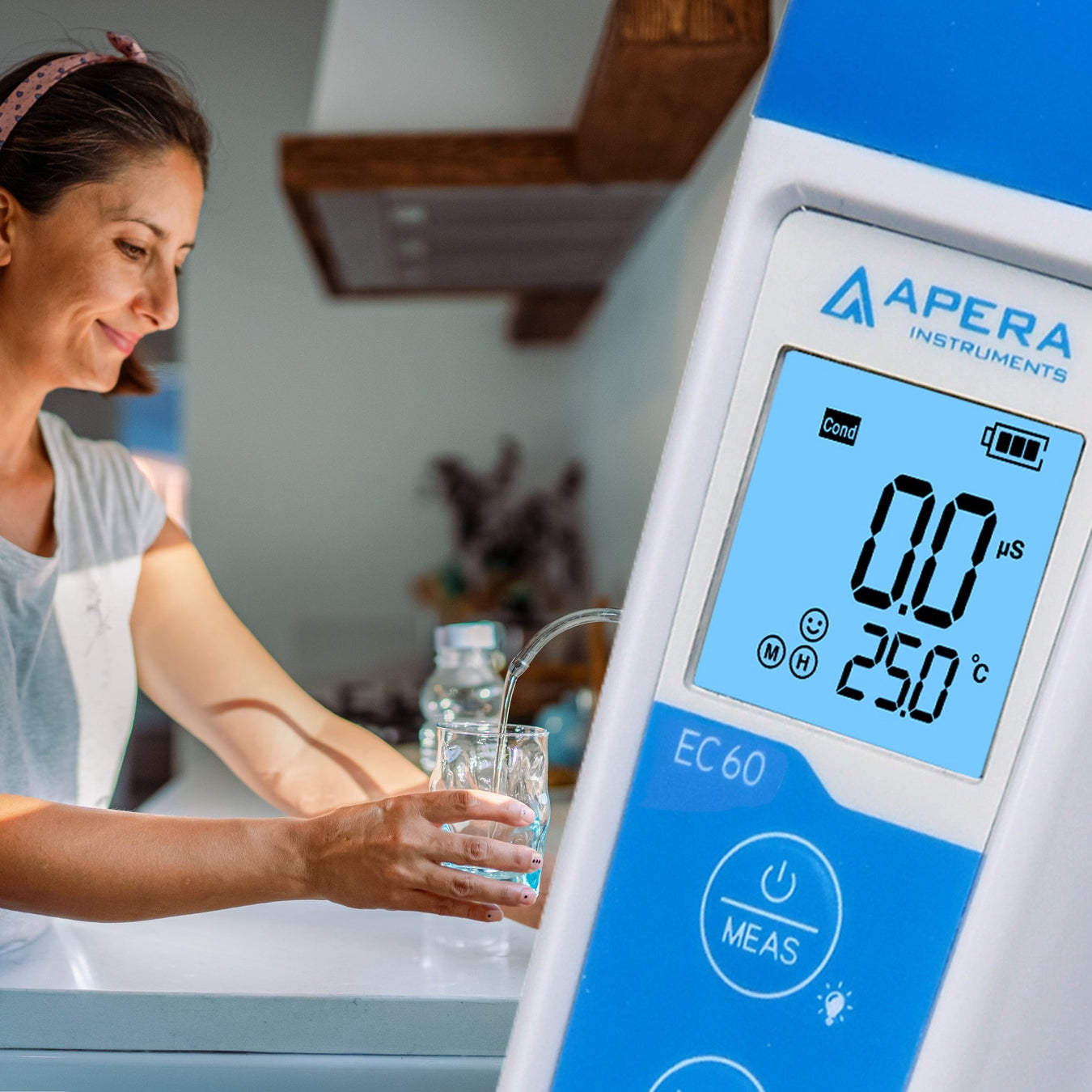 Woman washing dishes with a digital water quality meter displaying '0.0us' on the screen.